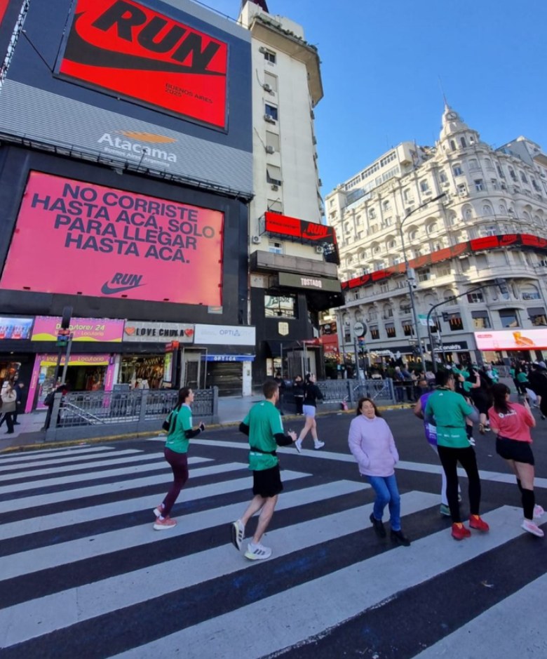 Pantallas de Nike frente al Obelisco durante el maratón de Buenos Aires, con corredores cruzando la avenida